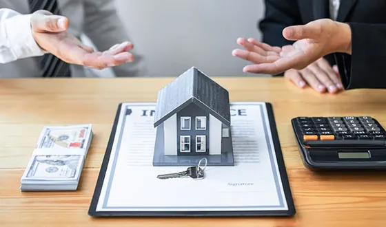 A financial advisor presenting a miniature house model on a clipboard with mortgage documents, symbolizing landlord loan options in Tampa FL.