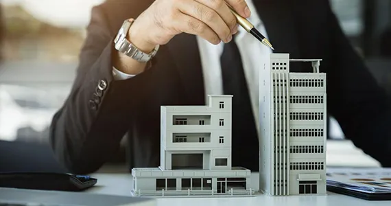 A business professional managing building models and financial elements, illustrating commercial landlord loan services in Chicago, IL.