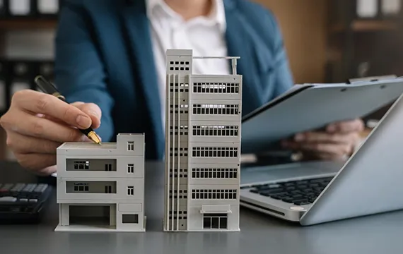 A businessperson analyzing financial documents with a model building, symbolizing commercial refinancing options in Tampa, FL.