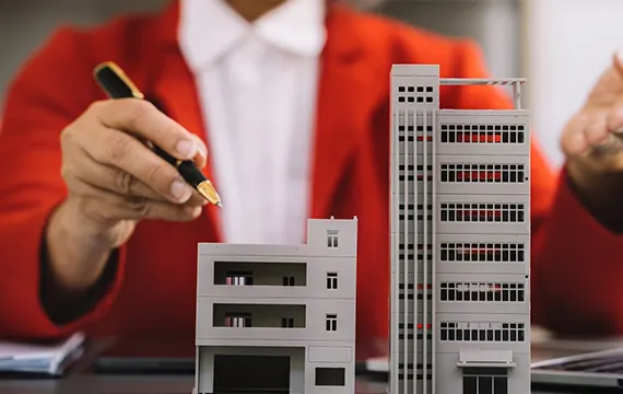 Person in a red suit holding a miniature building model, representing commercial short-term loan services in Memphis, TN.