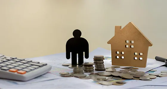 A financial setup with a miniature house, coins, and a small figurine representing short-term loan options in Memphis, TN.