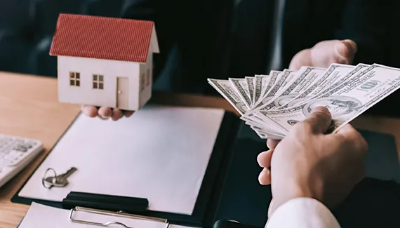 A real estate investor exchanging cash for a house model, symbolizing professional hard money lending services in Chicago IL.