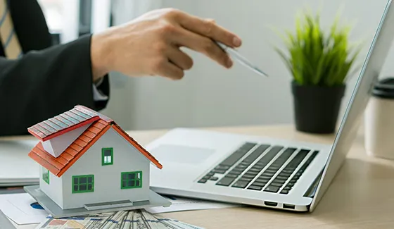 A person holding a miniature house model while discussing short-term loan options in Las Vegas NV.