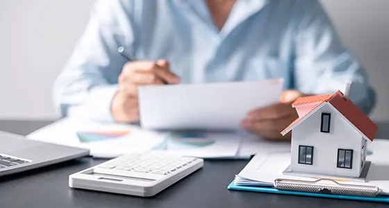 Financial advisor using a calculator and reviewing documents with a small building model, illustrating residential hard money loans in Chicago, IL.